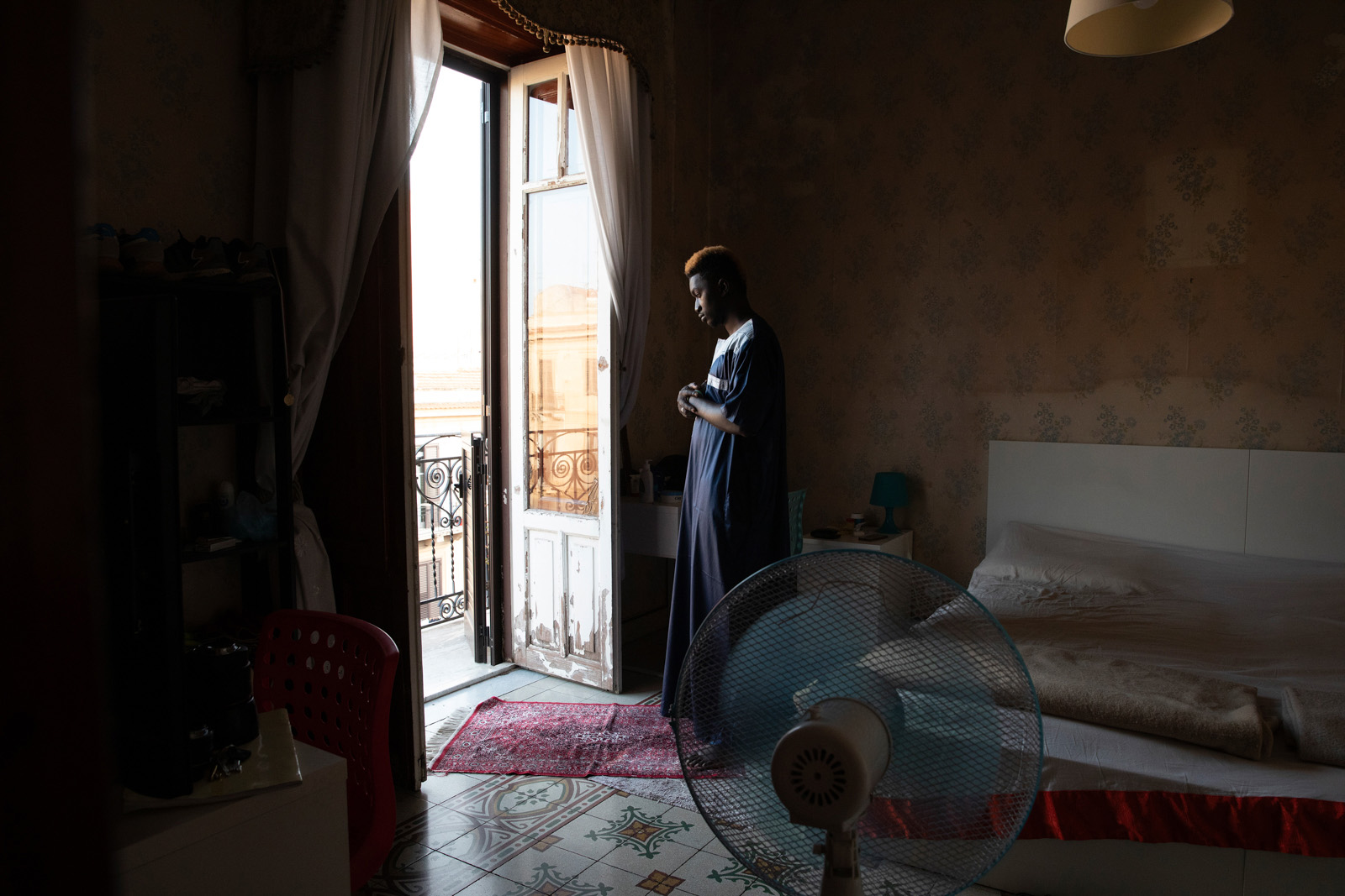 Actor Lamin Drammeh prays at home in the Ballarò area of Palermo, Sicily.