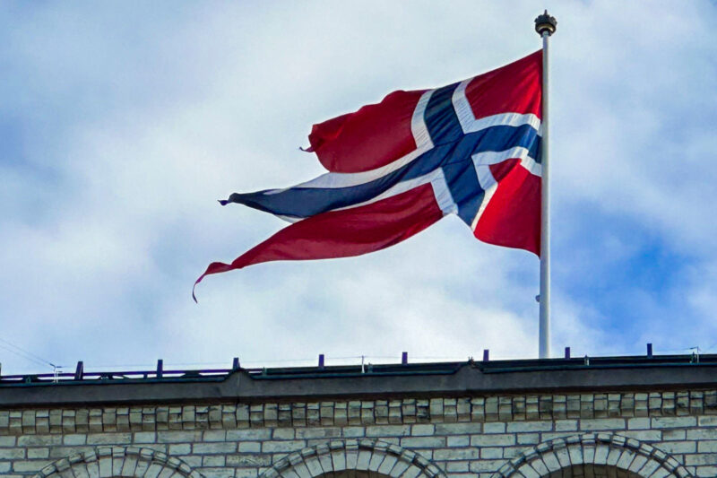 A close-up of a Norwegian flag, a white-bordered blue cross against a red background, flapping in the wind