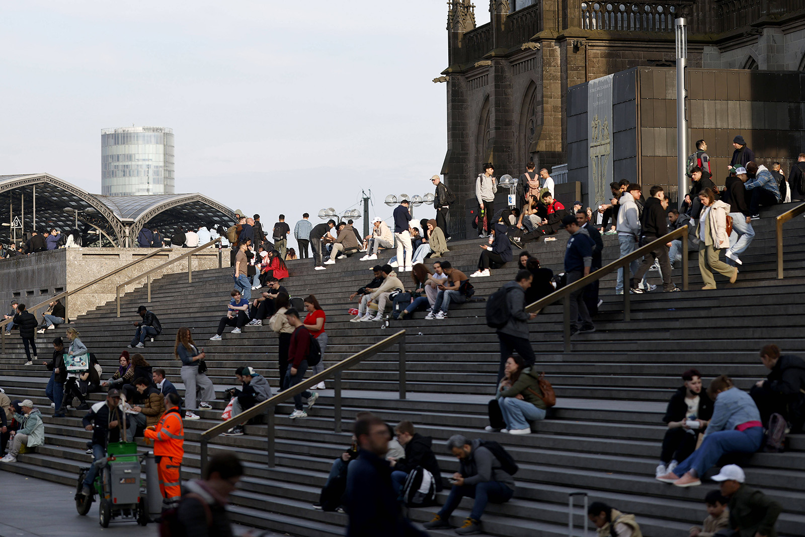 People sitting on the steps outside Cologne cathedral.