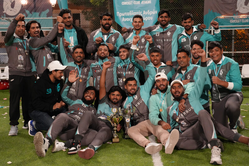 A smiling cricket team, clad in green, pose in rows for the camera