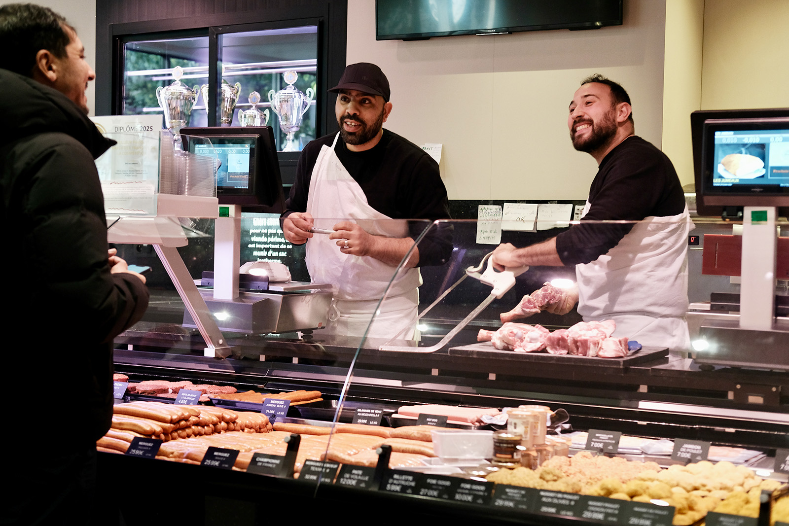 Slim Loumi (right) co-owner of Les Jumeaux, serving a customer at the halal butcher in Paris