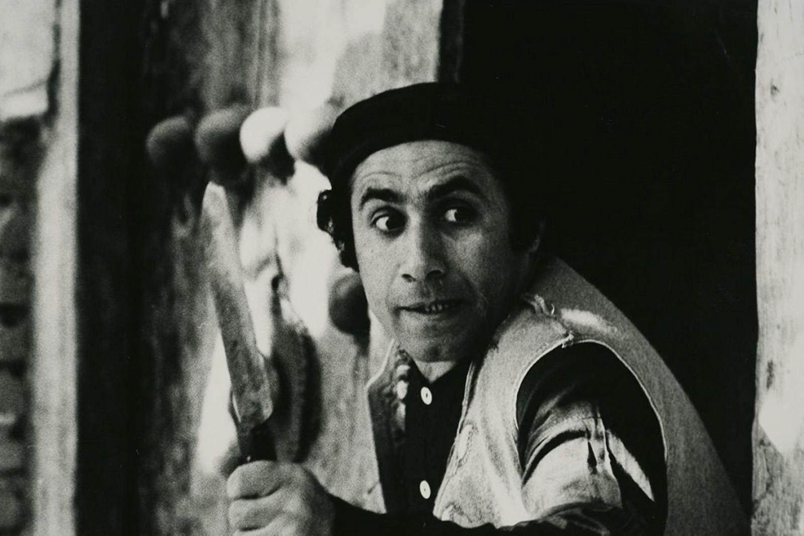 Film still from Secrets of the Jinn Valley Treasure (1974) directed by Ebrahim Golestan, showing as part of The Barbican's Masterpieces of the Iranian New Wave programming, 2026. Black and white image taken from film of a man holding a knife.