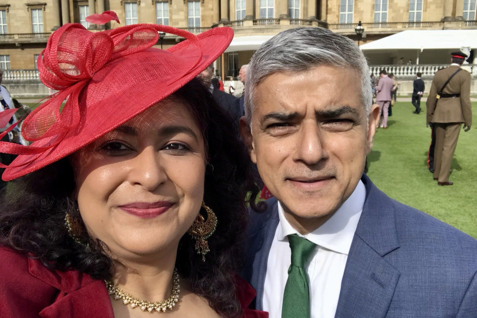 A selfie of Aysha Raza, smiling, in a red hat next to Sadiq Khan, also smiling, in a blue suit