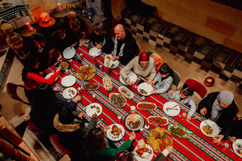 A photograph showing people seated at a table enjoying iftar at Palestine House, London