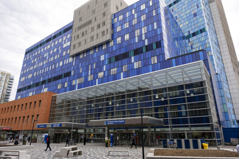 An exterior view of the Royal London Hospital, with glass in the lower half and blue and grey panelling above it