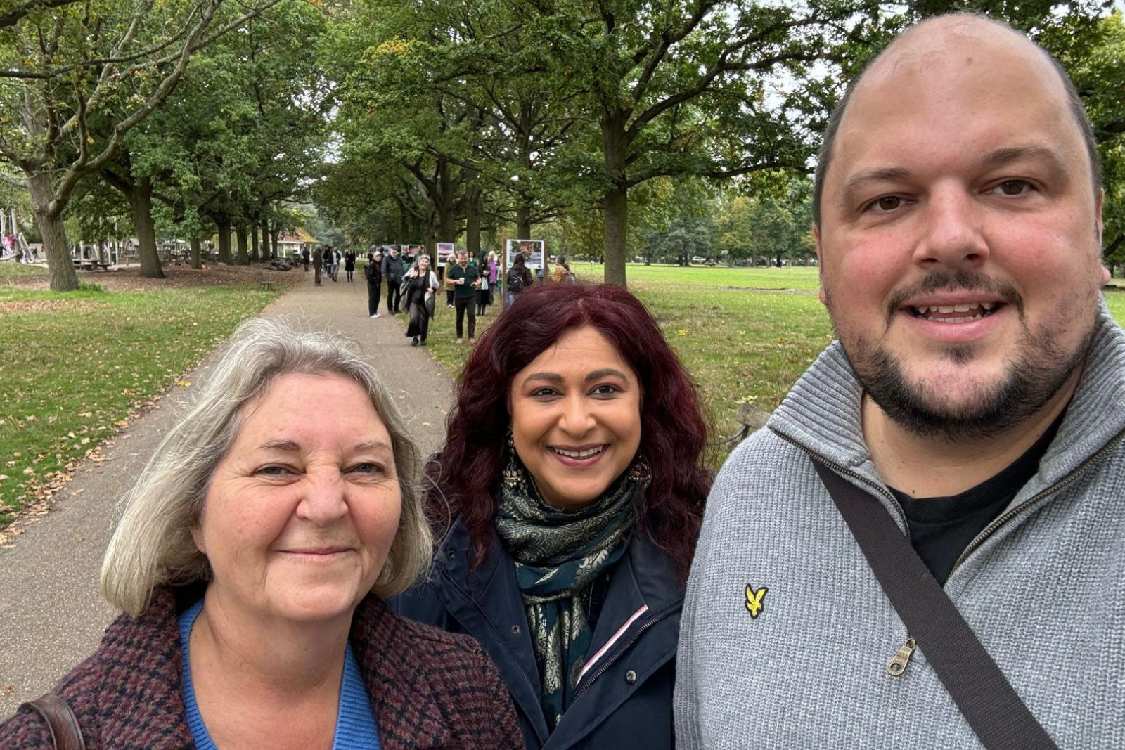 A selfie of three smiling figures in a park