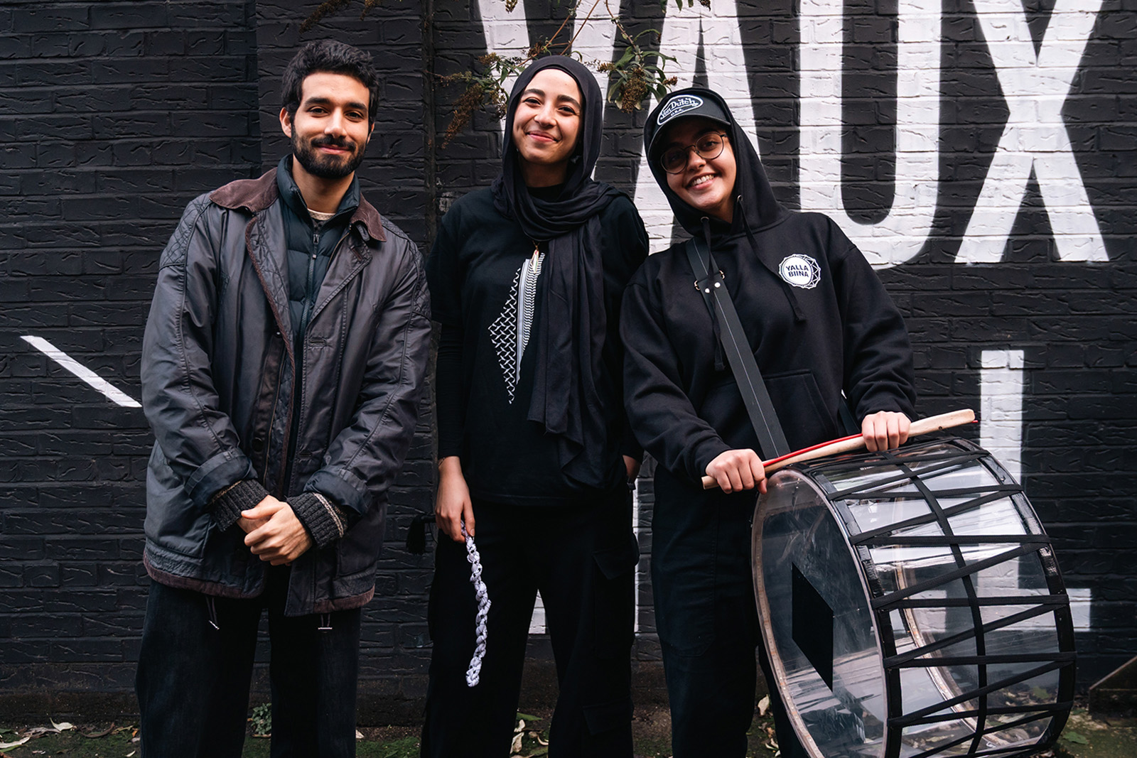 A photograph of DabkeRoots founder Omar El-Zeinab (on the left) with two members of his team, one holding a drum and drum sticks
