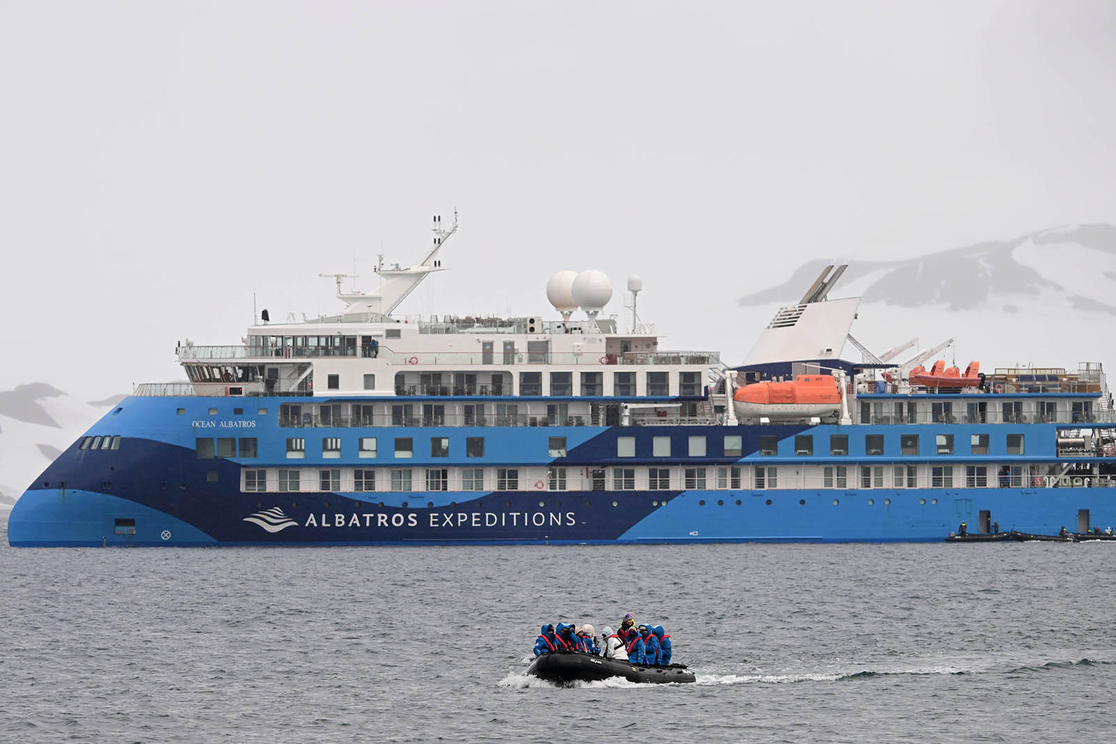 A photograph of Antarctic boutique cruise ship Ocean Albatros, with, in the foreground, a group of passengers moving away from the vessel on a Zodiac boat excursion