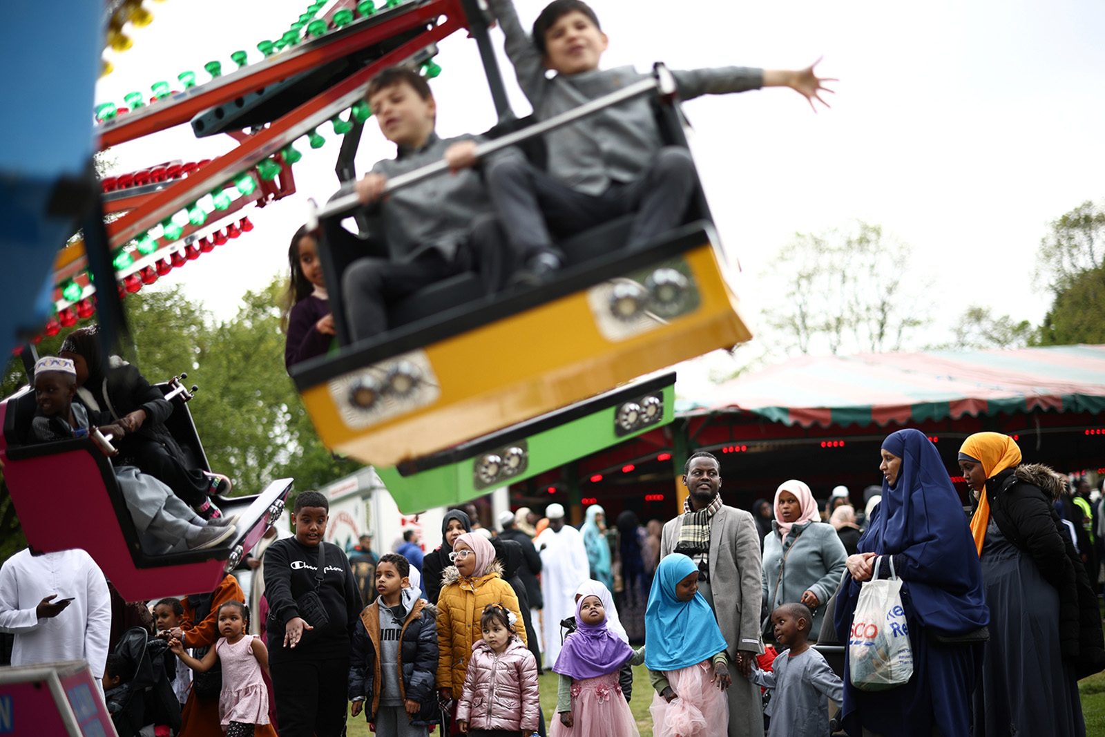 A photograph featuring, in the foreground, children on a funfair ride, during Eid al-Fitr celebrations at Small Heath Park in Birmingham in May 2022