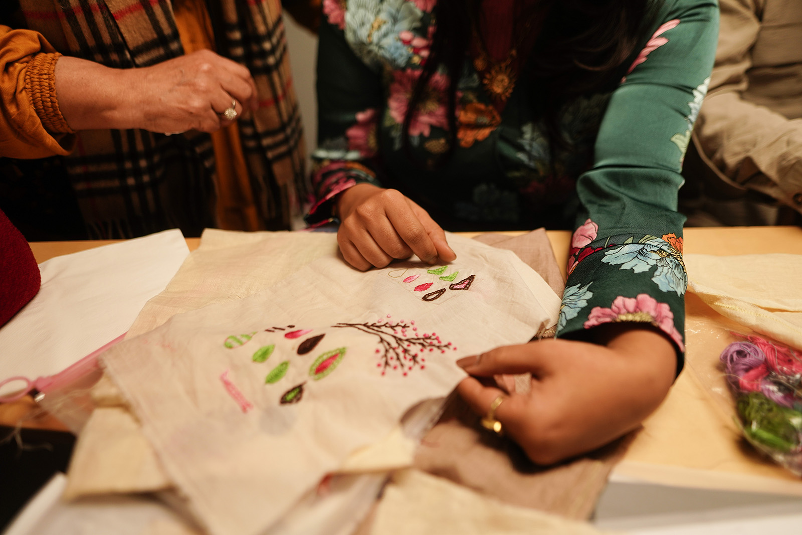A photograph showing two Homelore workshop attendees inspecting some of the embroidery being created for their Lisbon exhibition Taking Root