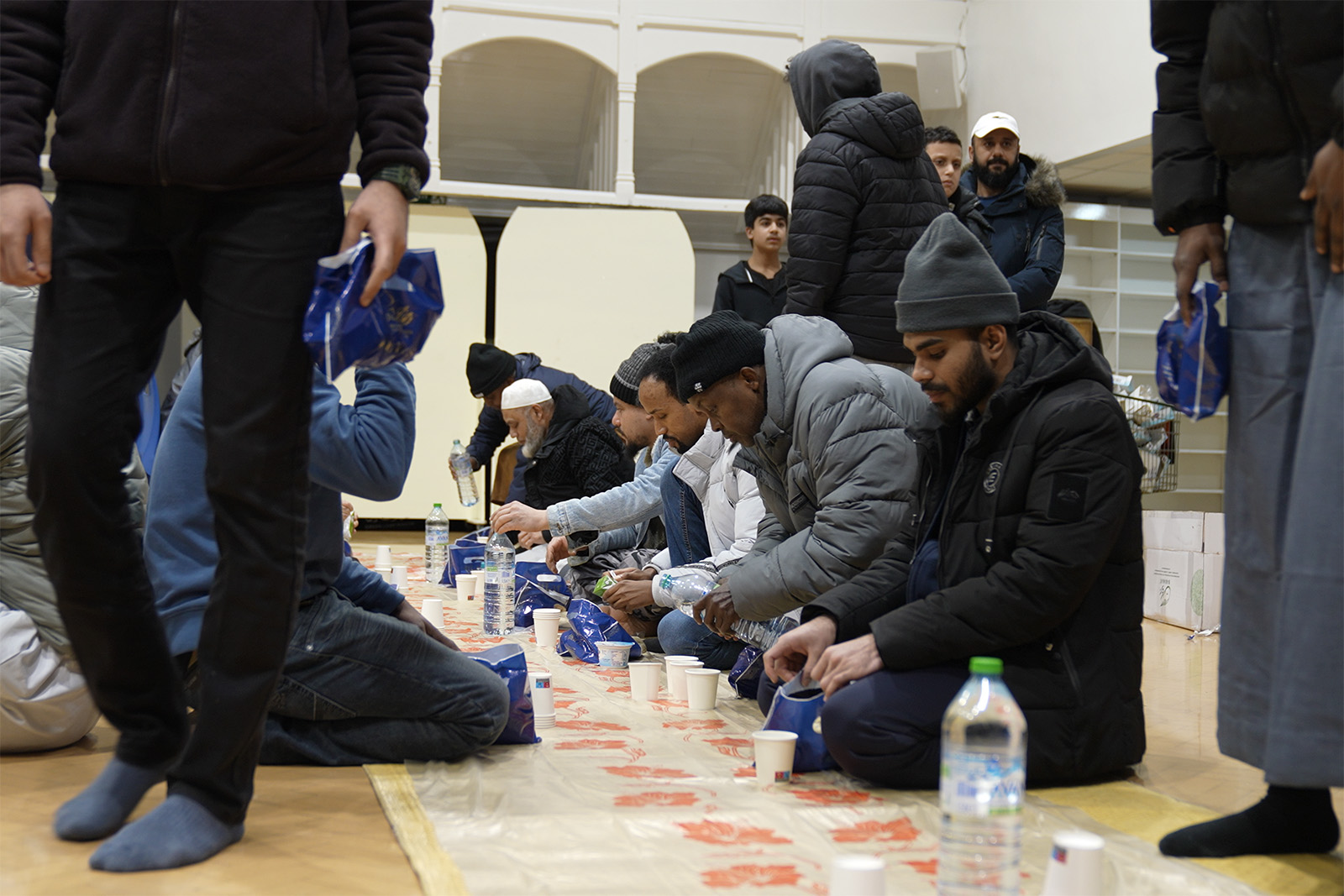 A photograph showing worshippers kneeling down having iftar at Green Lane Masjid, Birmingham