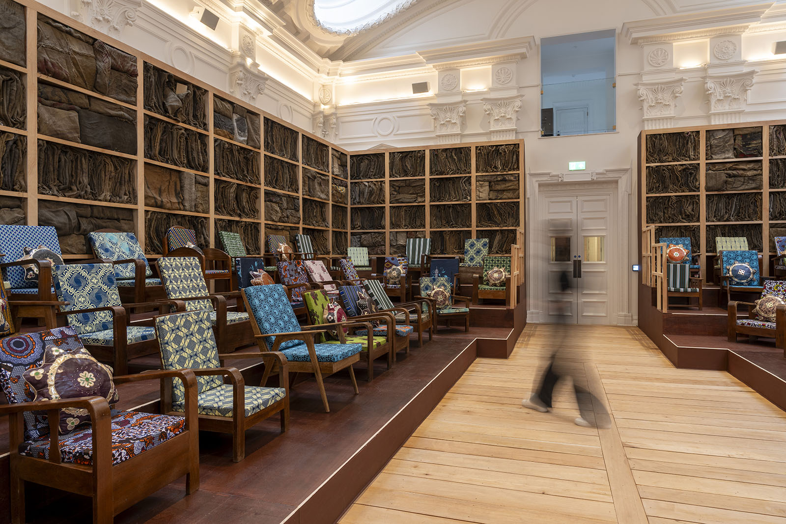 A photograph of Ibrahim Mahama's installation Parliament of Ghosts featuring chairs brought from households across his native Ghana, in Ibraaz's Majlis, a large room with a high ceiling that was formerly the building's great hall