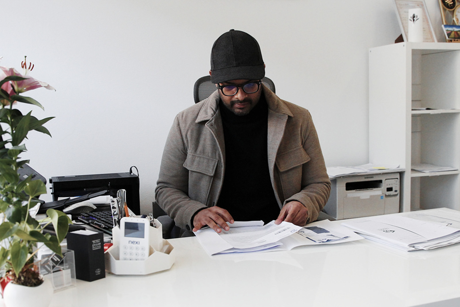 A photograph of Monfalcone local councillor Sani Bhuiyan seated at his desk, studying some documents