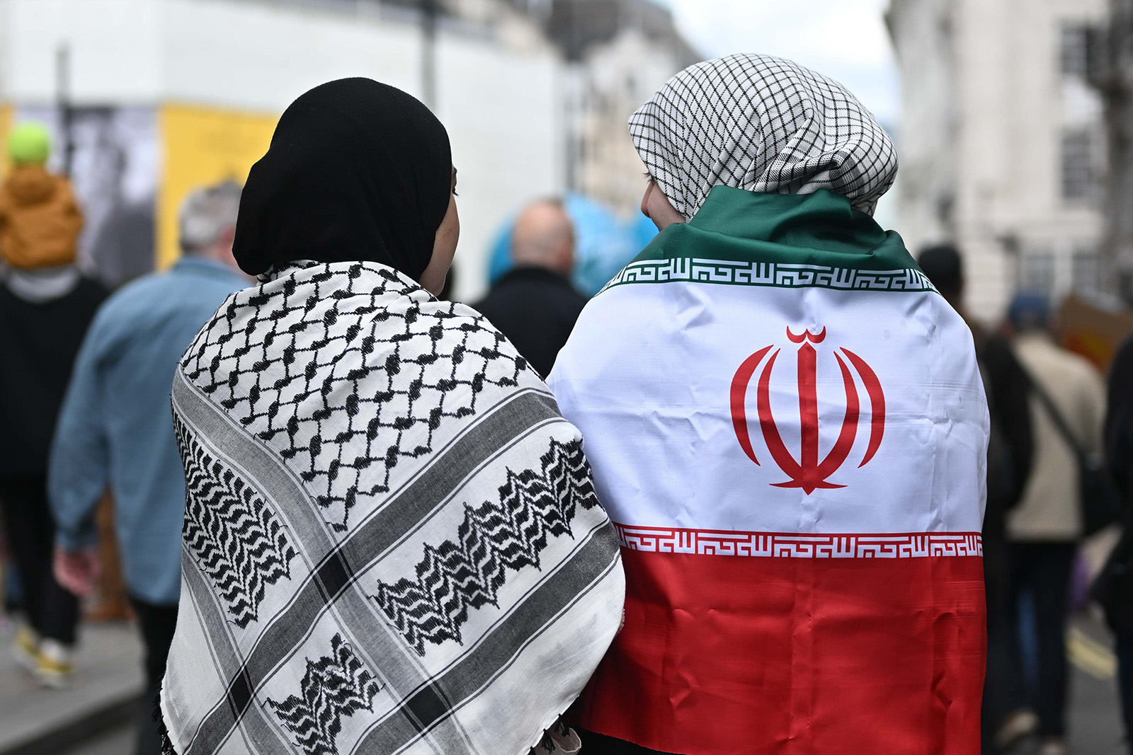 Two female protestors, one with a keffiyeh draped around her shoulders, the other with an Iranian flag, during the Together Alliance rally in London on Saturday 28 March 2026