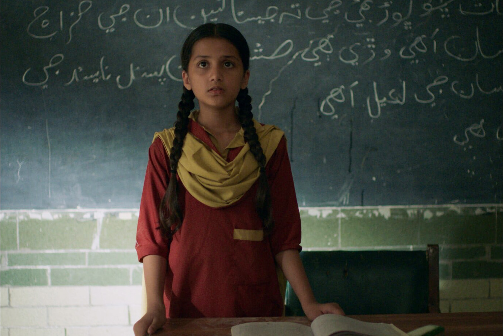 A still image of Nazualiya Arsalan as Rabia, who is standing before a blackboard in a classroom, in Seemab Gul’s Ghost School, which opens the UK South Asian Film Festival 2026