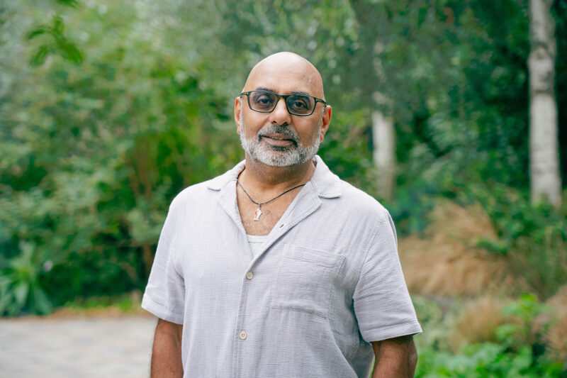 A portrait photograph of Asad Rehman, chief executive of Friends of the Earth UK, wearing an open-collared short-sleeved shirt