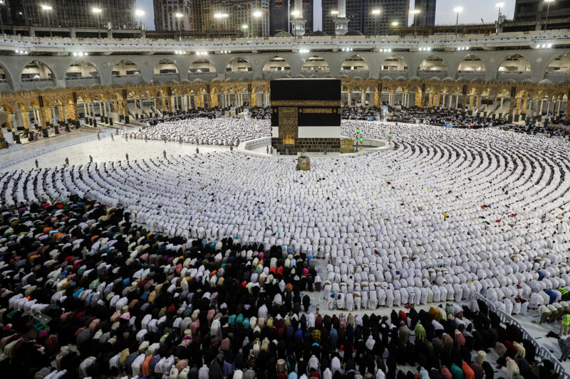 A photograph of Muslim worshippers and pilgrims (dressed in white) praying around the Kaaba at the Grand Mosque in Mecca, during Hajj in 2022