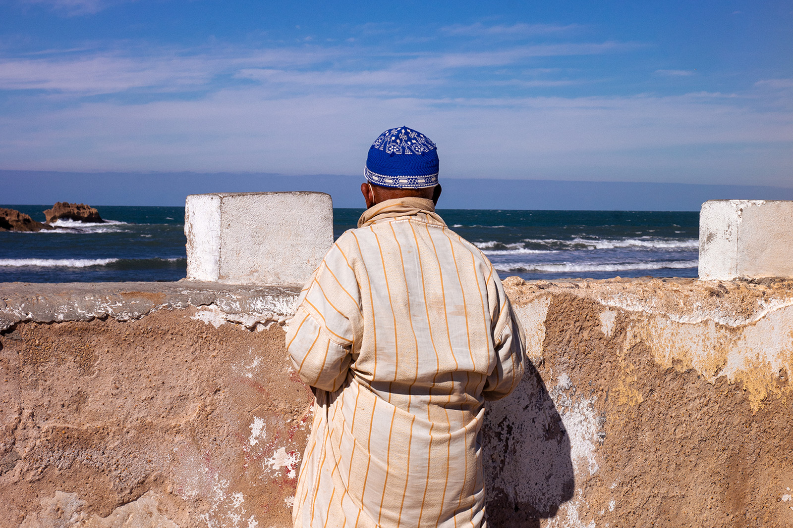 An image of a man looking out to sea, taken from behind. From the series Suzanne, Long Road by Mayssa Jaoudat, part of her wider photographic project Mille-Feuilles