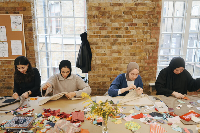 A photograph of women participants at an Upcycled Sajada workshop making their own prayer mats