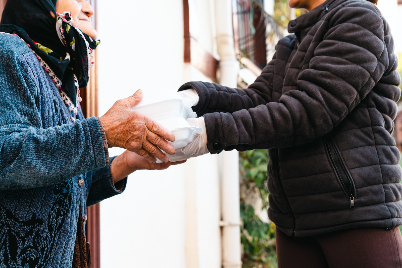 A stock image of a charity volunteer handing over a food delivery to an elderly woman on her doorstep
