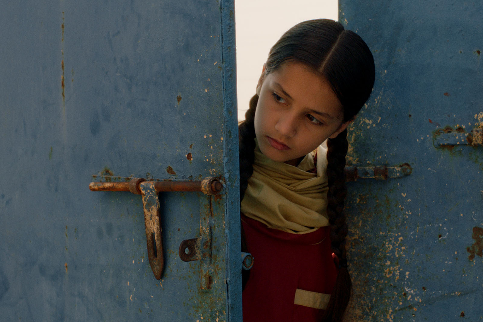 A still from Seemab Gul's feature film debut, Ghost School, featuring Nazualiya Arsalan as the main protagonist, 10-year-old Rabia, peering round a partially opened door