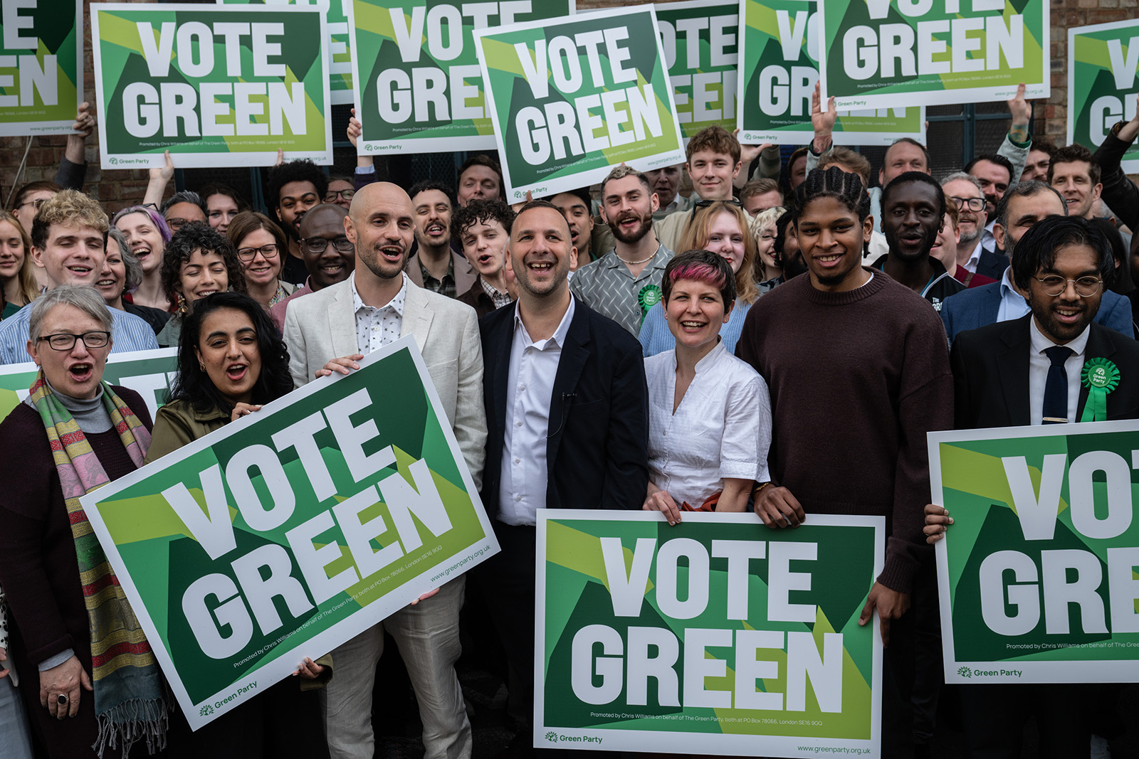 A photograph of Green Party leader Zack Polanski, surrounded by supporters with 'Vote Green' placards, at a local election campaign event on 9 April 2026