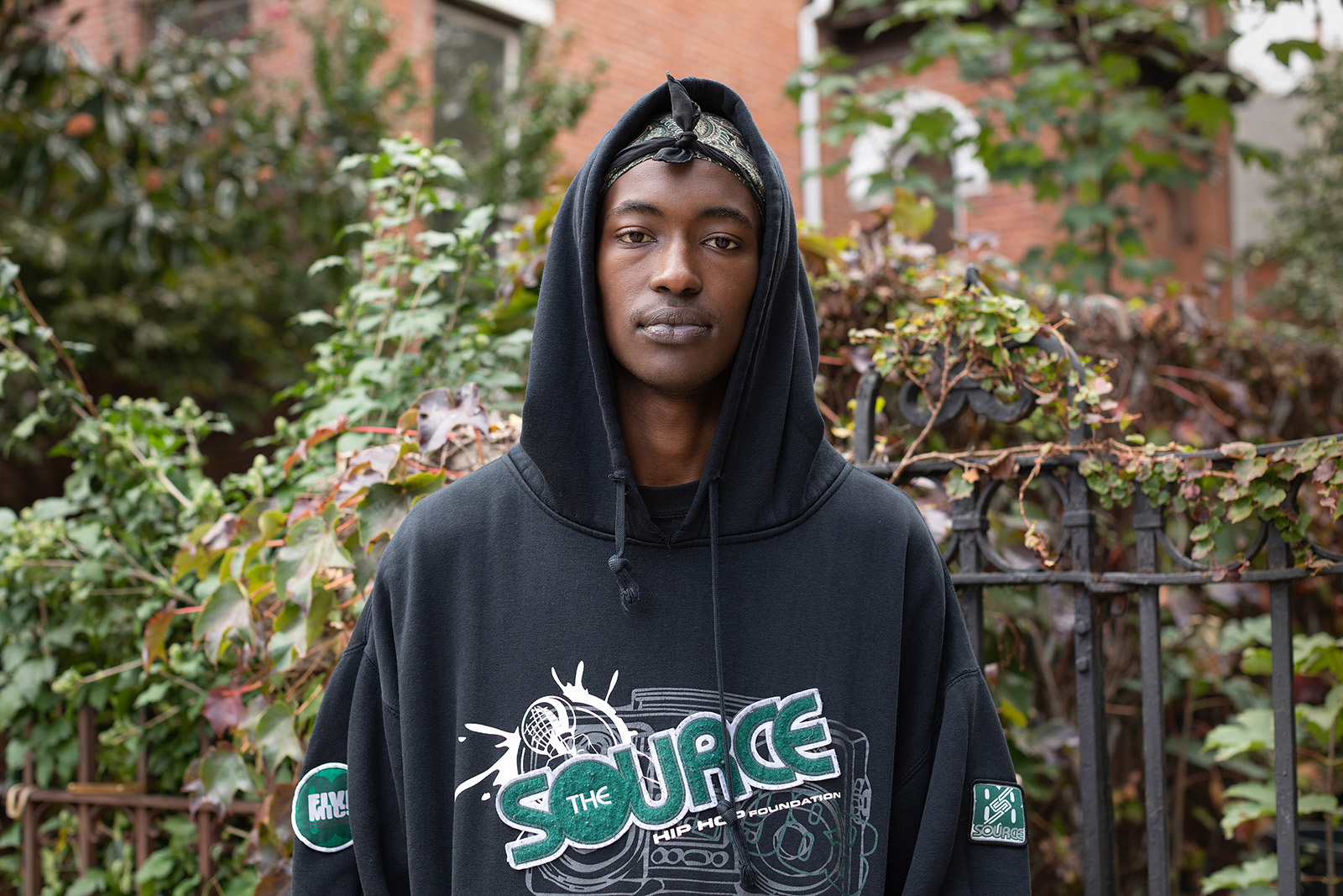 A photograph of a young man, Abdoulie Ibrahim Faal, wearing a hoodie and looking into the camera, taken in New York in 2021