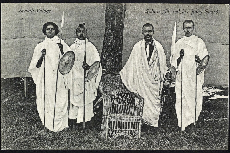 A black and white archive photograph of four Somali men who formed part of the Somali Village troupe at the Bradford Great Exhibition in Lister Park. Sultan Ali al-Urfa (second from right), leader of the Somali Village, selected members of his extended family and clan for the project