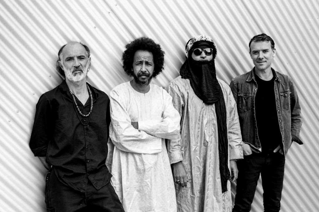 A black and white photograph of the four members of Tuareg band Tamikrest