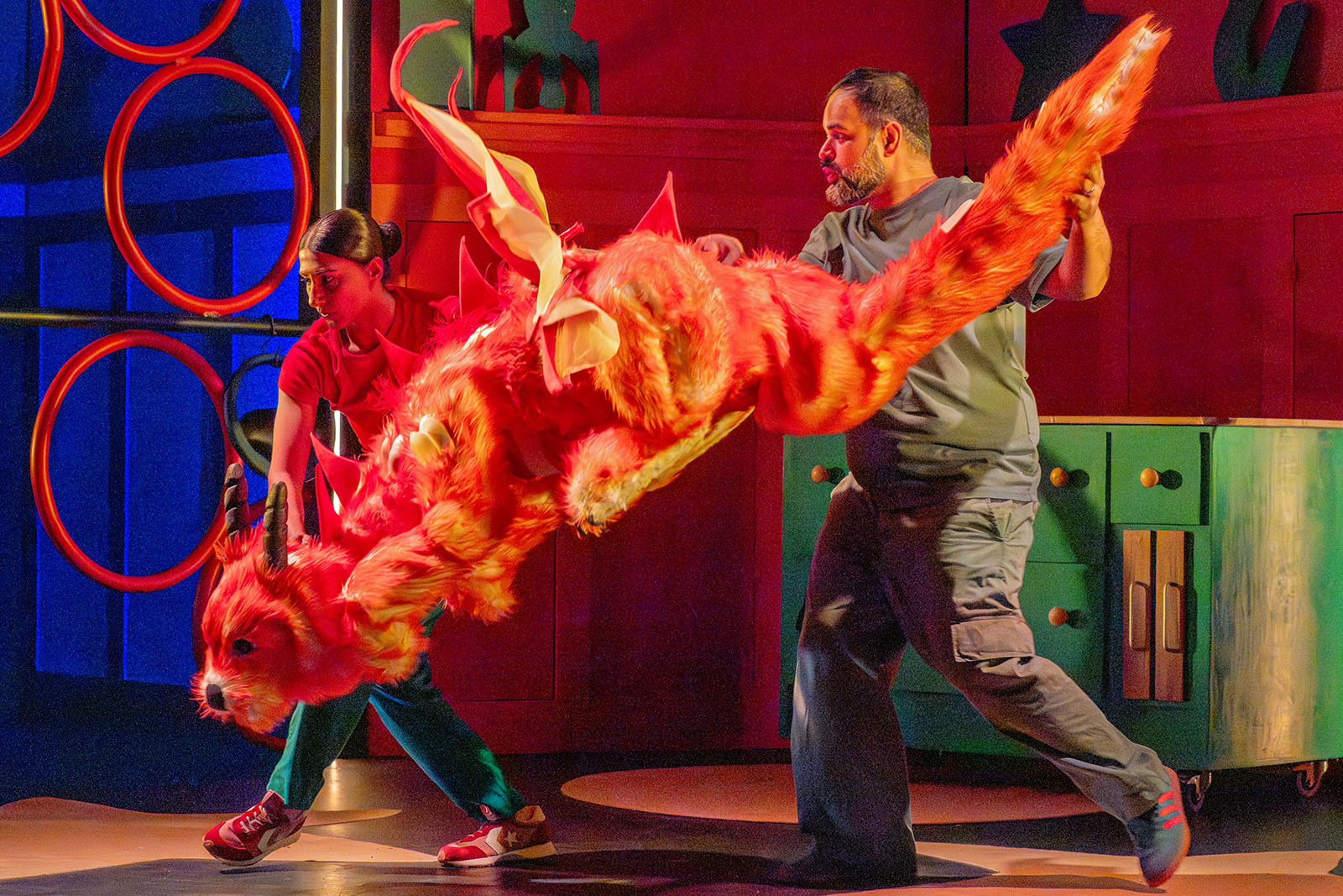 A production still of two puppeteers on stage with the flying dragon featured in Planet Omar