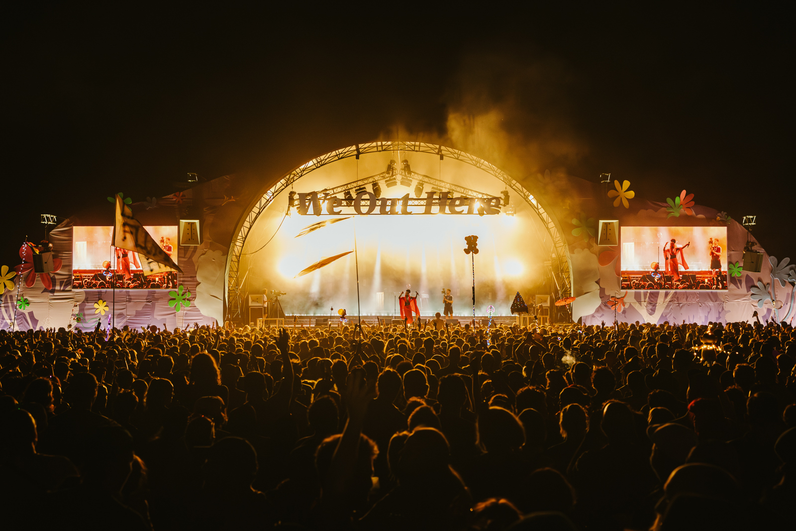 A photograph with a view over the audience towards a brightly-lit stage during an evening performance at We Out Here festival