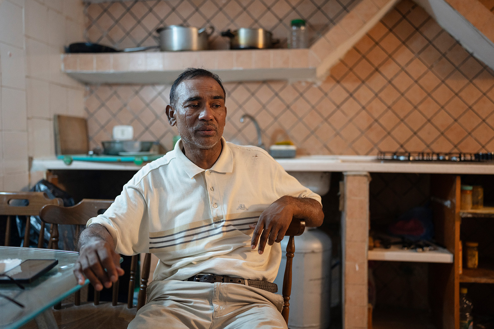 A photograph of Gias Uddin sitting at a table in a kitchen in Naples