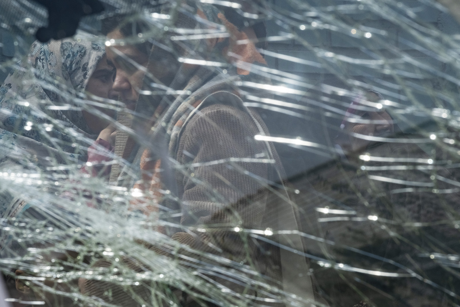 A photograph taken through a shattered vehicle windscreen of Iranian women standing in the street following a US-Israeli strike in Tehran in March 2026