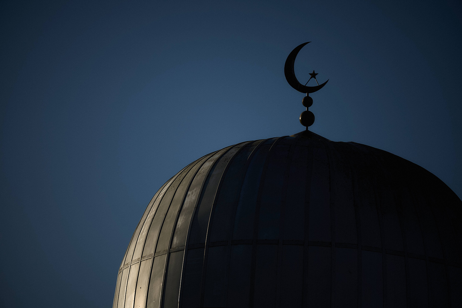 A silhouette of the dome of a mosque against a dark sky