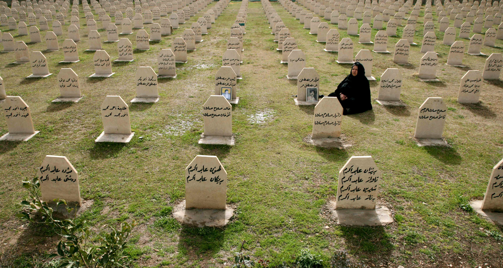 A photograph of an Iraqi Kurdish woman visiting the grave of her relatives, Hafkar Omar Mustafa and Neghin Mustafa, who were killed in a gas attack by Saddam Hussein's regime in 1988 at the memorial site for the victims in the town of Halabja, in 2012