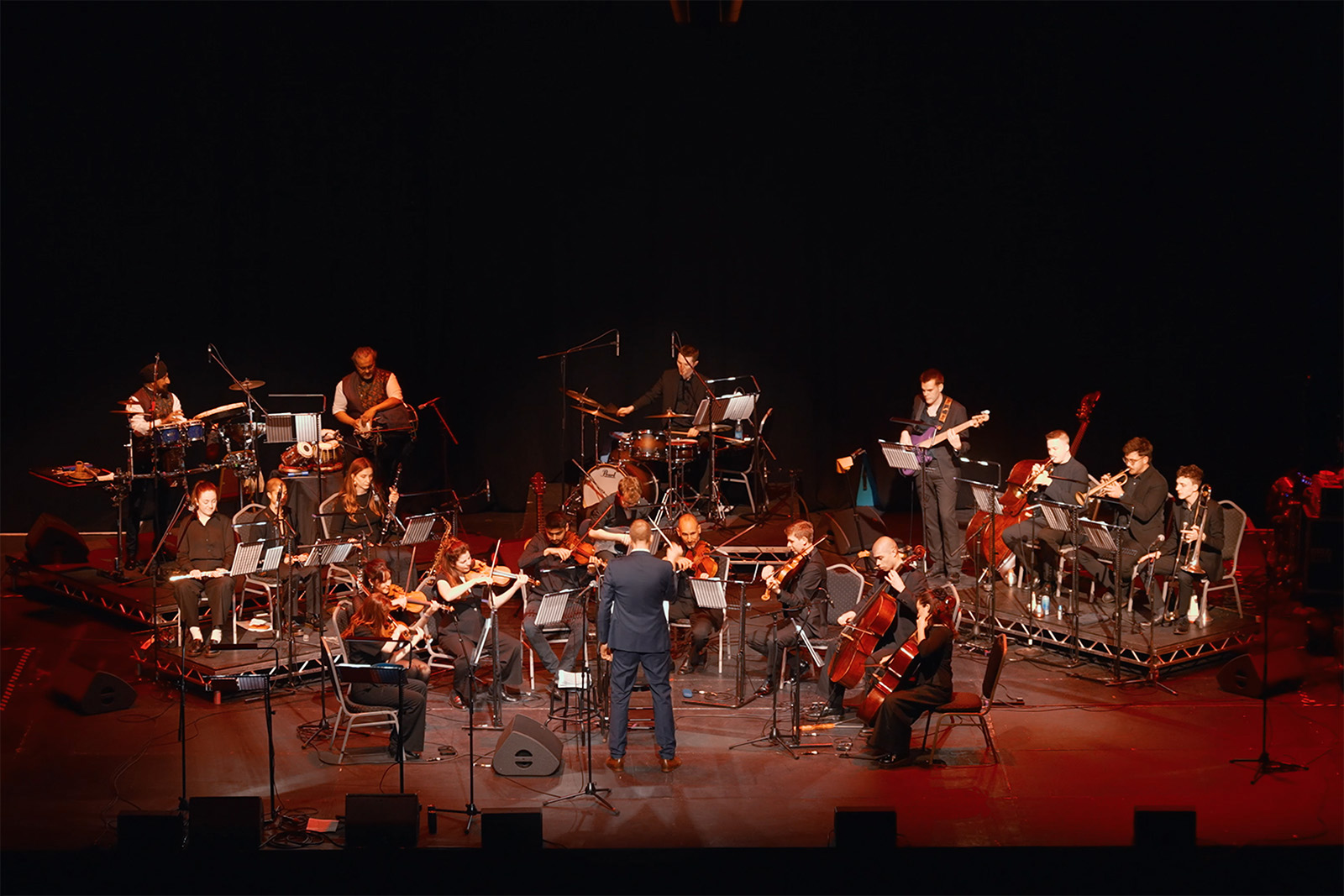A photograph of Tim Pottier conducting the London Bollywood Orchestra at Alexandra Palace in April 2026