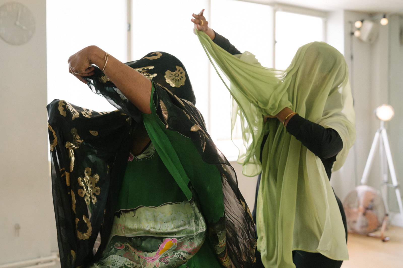 A photograph of two women taking part in a Buraanbur Sahlan session while wearing diracs — flowing traditional Somali dresses — and garbasaars over their heads
