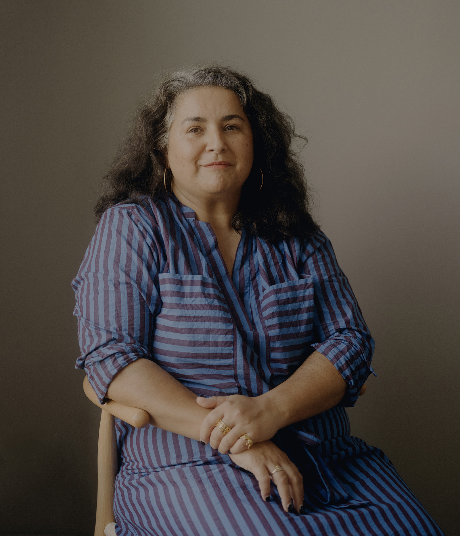 A portrait photo of Shaheen Baig, who  is seated and looking at the camera, smiling