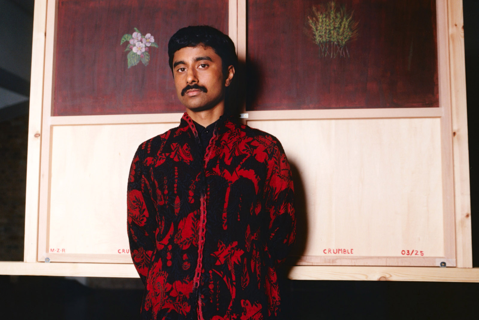 A portrait photograph of Mohammed Z Rahma, who is wearing a red and black patterned jacket