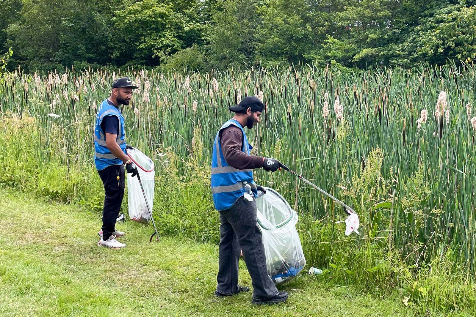 Two volunteers holding bags litter picking at a canal in the West Midlands during Muslim Climate Action Week