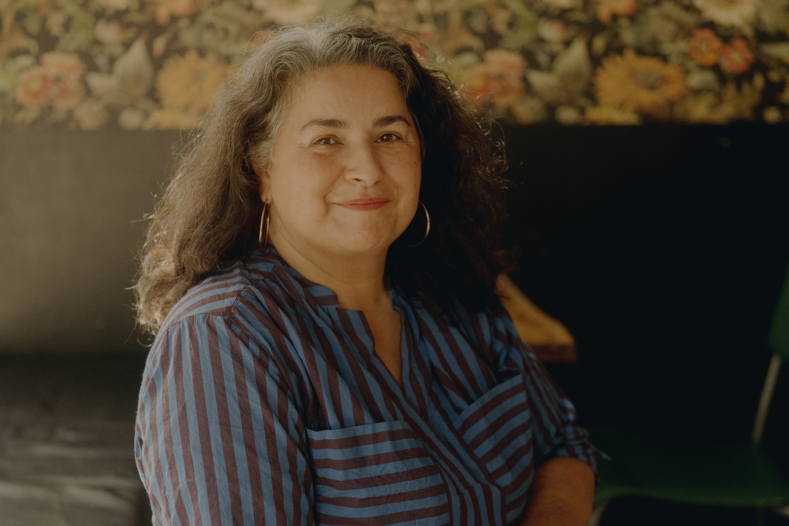 A portrait photo of Shaheen Baig, who is seated and looking at the camera, smiling