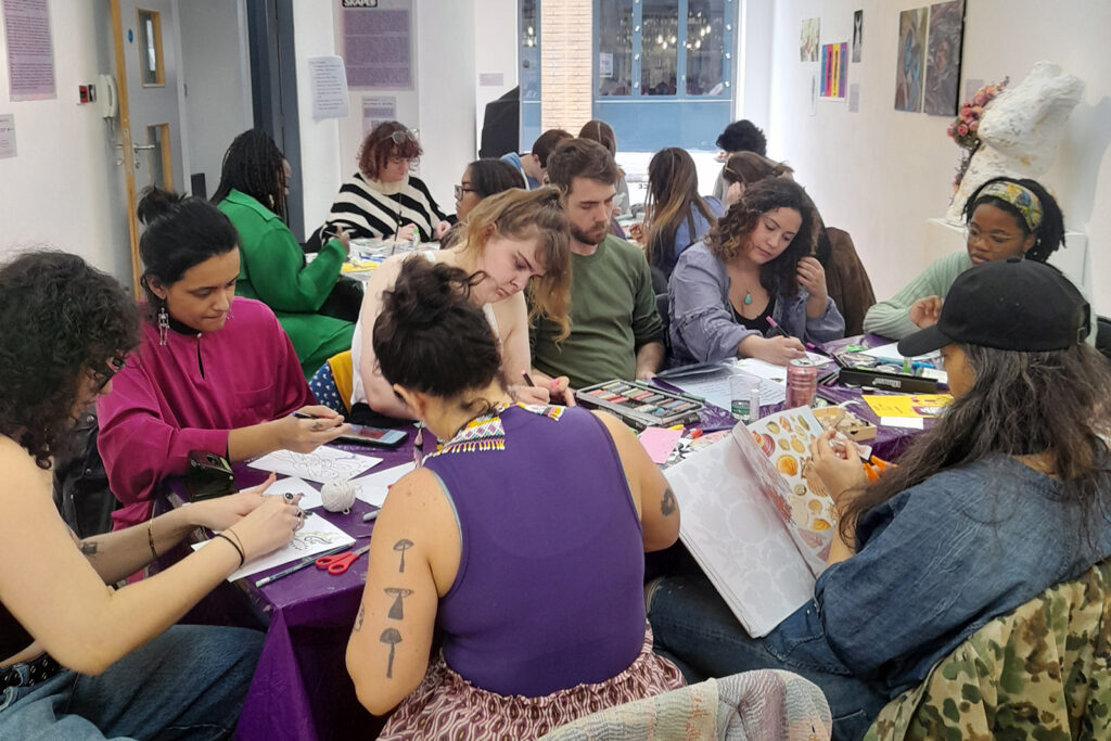 photograph of Skaped workshop, image shows young people around a table making posters.