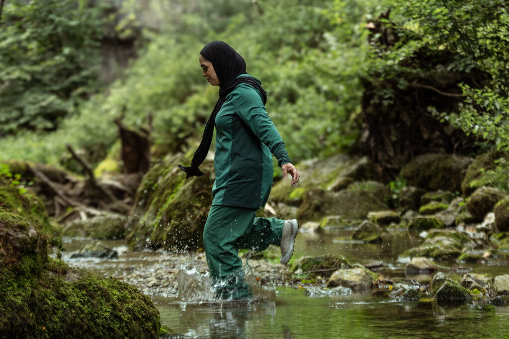 Woman wearing green active gear in wooded environment.