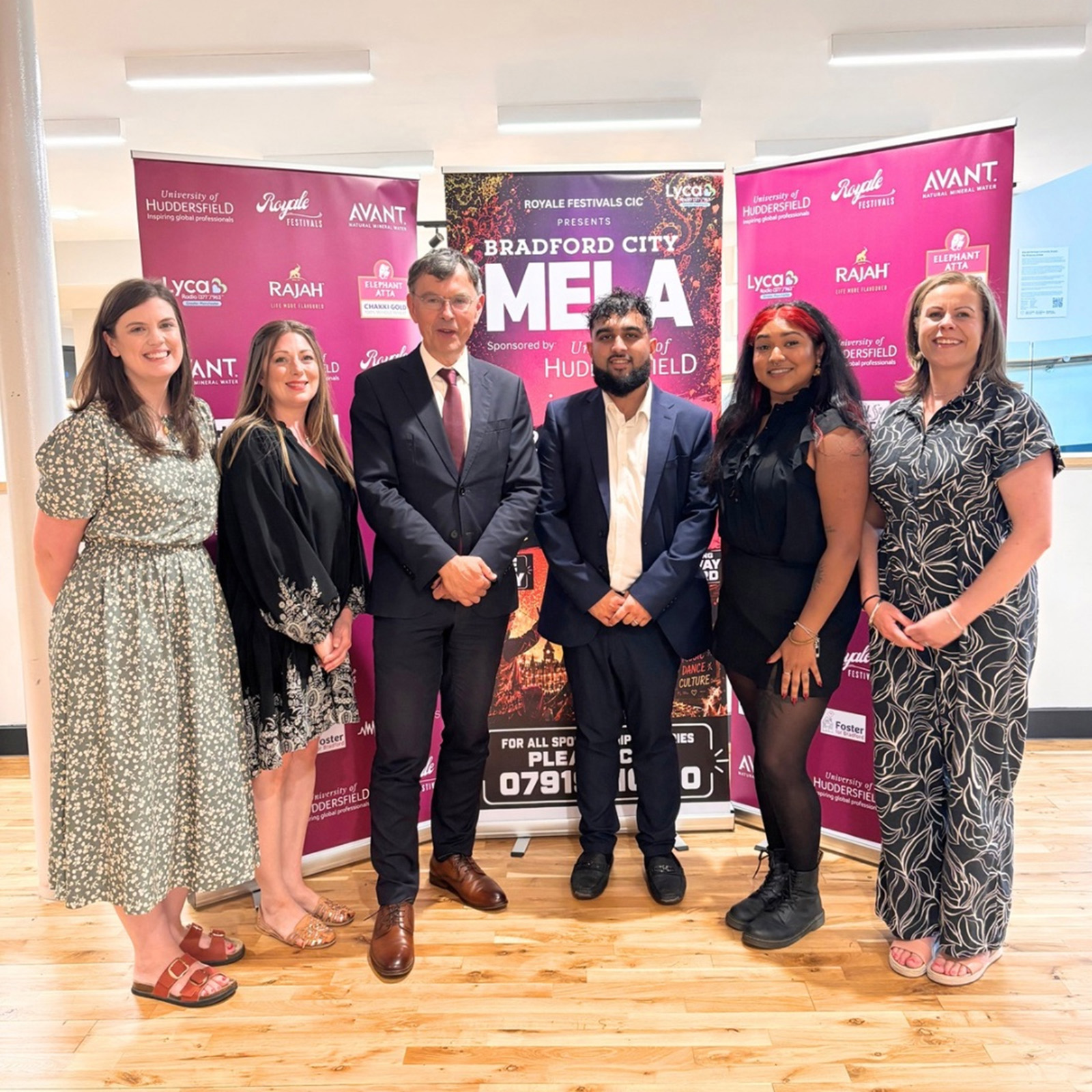 A publicity photograph of Danyul Khan (centre right), director of Bradford City Mela organiser Royale Festivals, with Tim Thornton (centre left), deputy vice chancellor of event sponsor Huddersfield University, in a group shot with four women