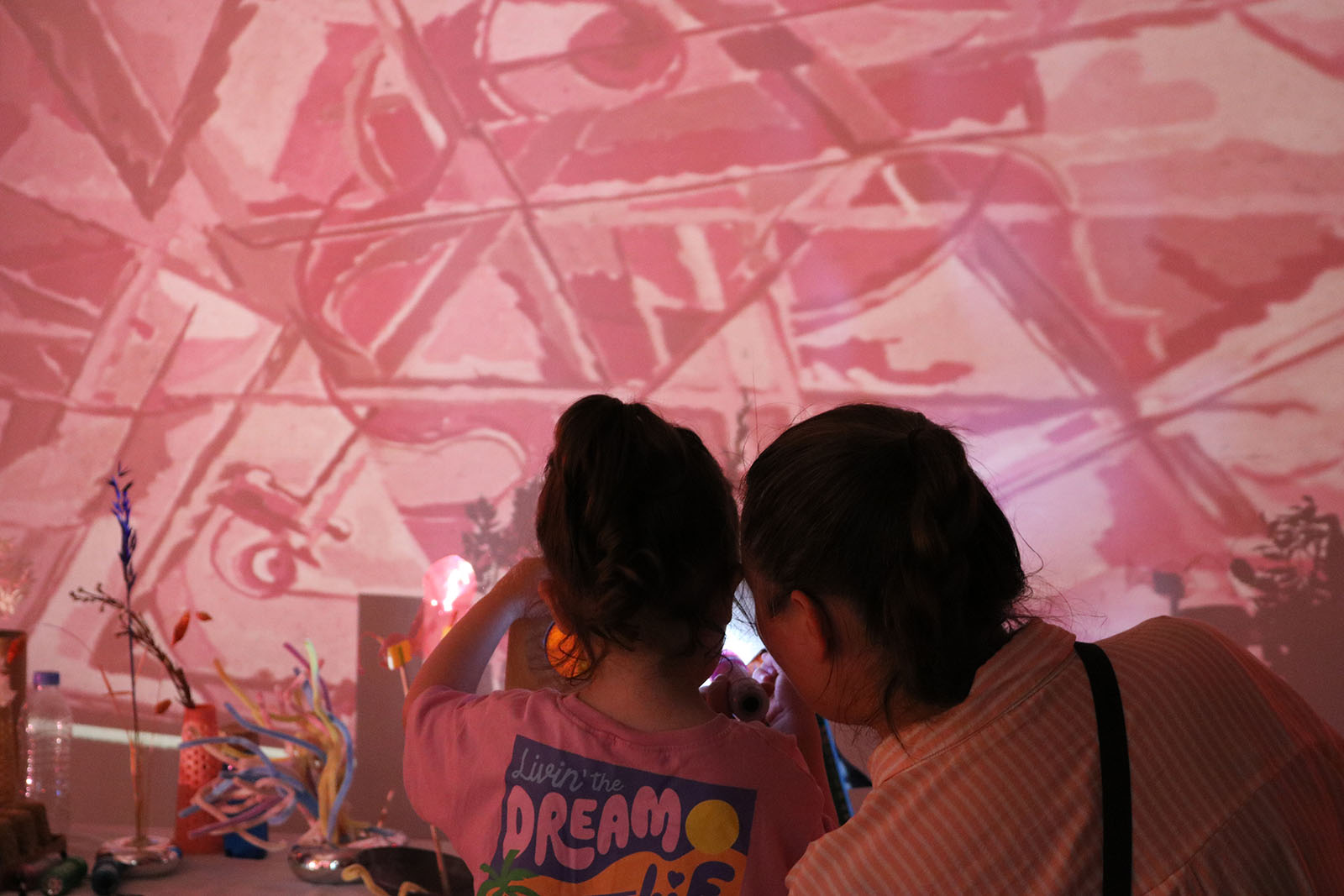 A photograph of creative sensory-play installation Play Lab: Lum’a at Mosaic Rooms, south-west London, with a mother and child in front of what appears to be a large image projected on a wall