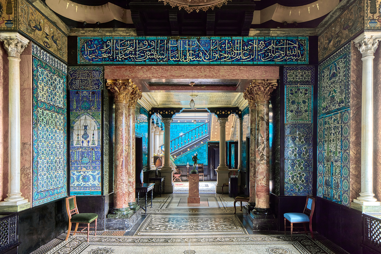 A photograph of the Arab Hall at Leighton House, featured ornate blue-tiled walls, some inscribed with Arabic writing