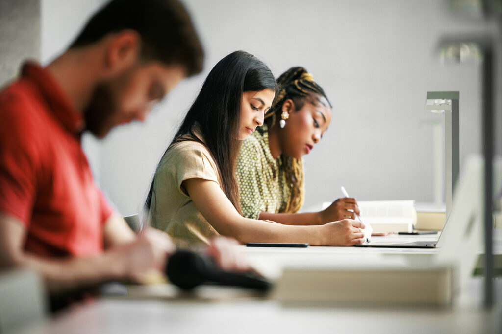 Three young people in profile studying at separate desks