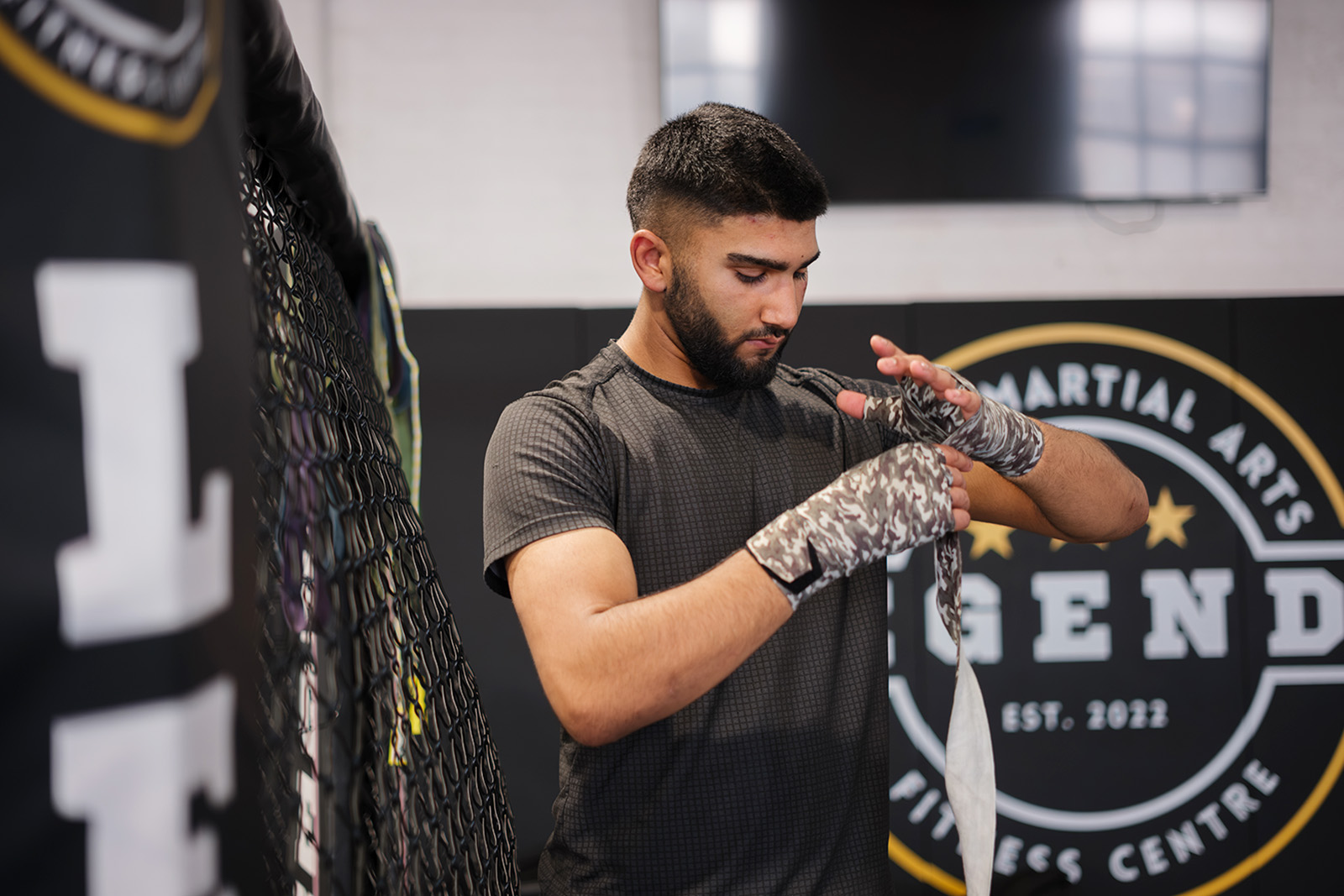 A photograph of Muhammad Eesa strapping up his hands before putting on boxing gloves for a training session at Legends MMA and Fitness Centre in Luton
