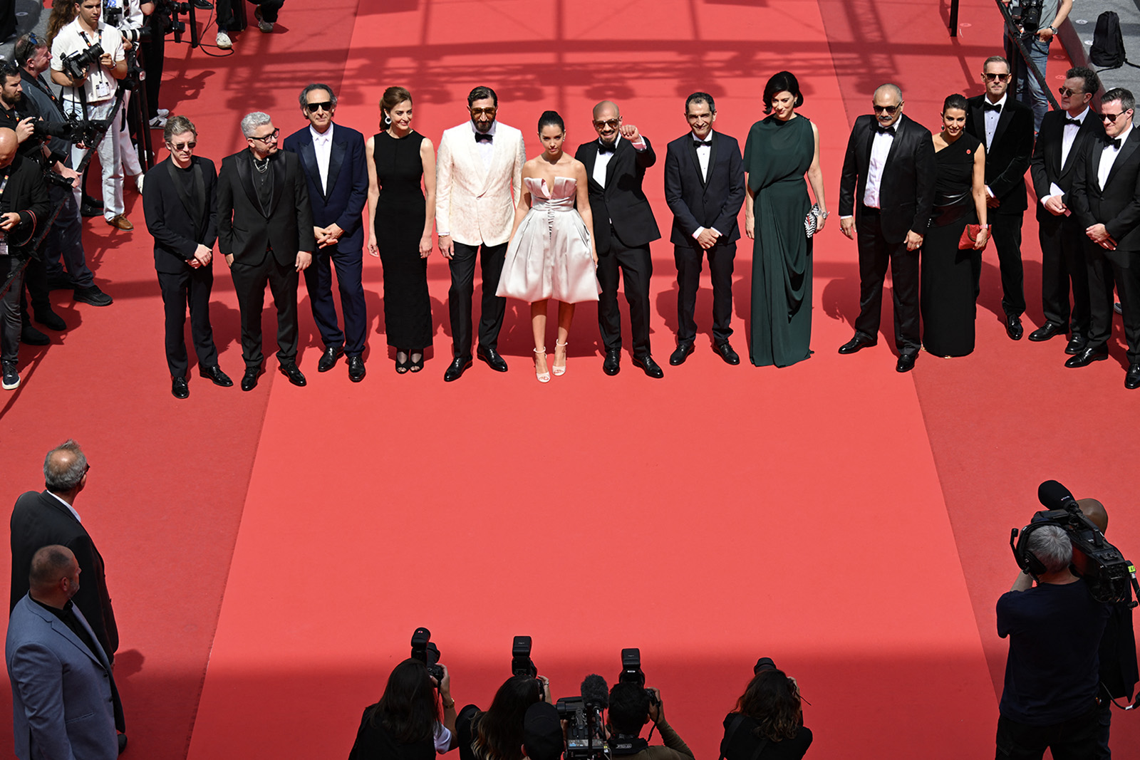 A photograph of Linda Mutawi on the red carpet at the Cannes Film Festival in May 2025 for the screening of Eagles of the Republic, in a group shot with the main cast and director of the film, Tarik Saleh. Mutawi (4th from right) is wearing a black off the shoulder black dress and carrying a red hand bag