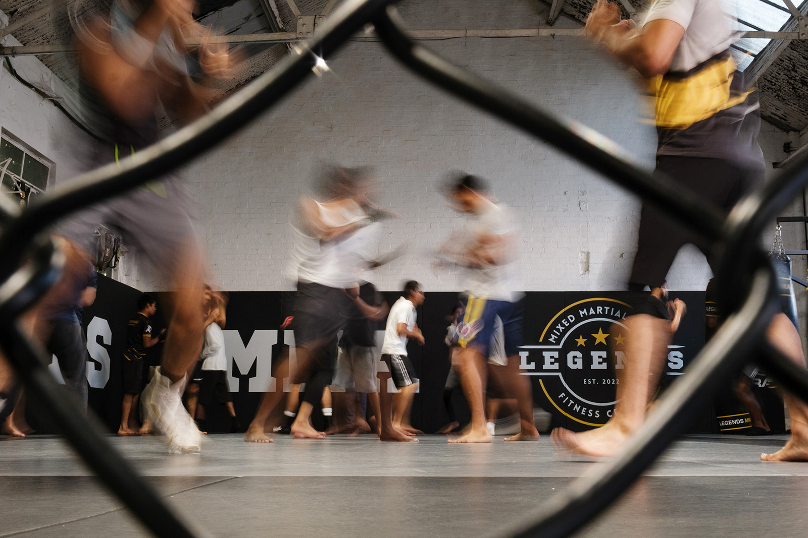 A photograph of people sparring, with the bodies in motion and blurred, at a men's boxing session at Legends MMA gym in Luton